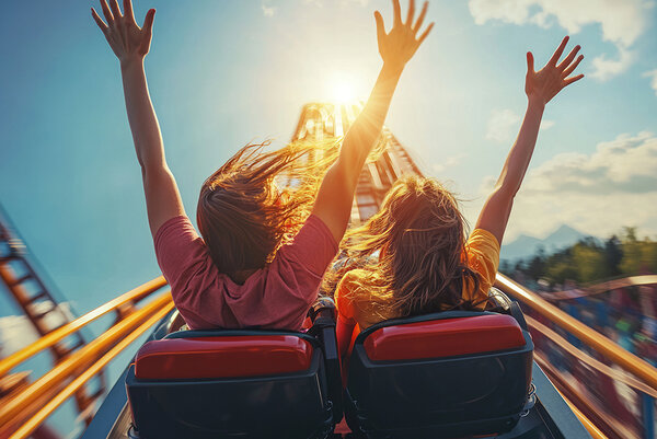 Two friends raising their arms on a thrilling roller coaster rid