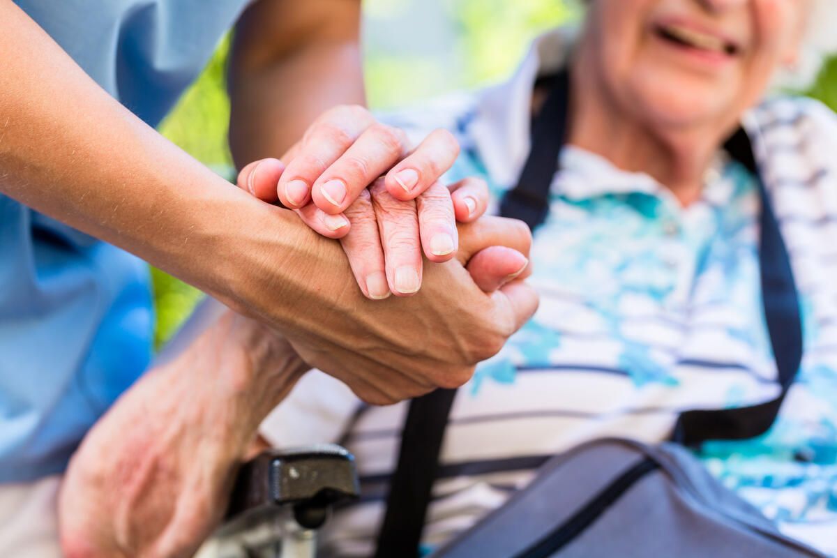 Bild vergrößern: Ein Pfleger hält einem Senioren die Hand