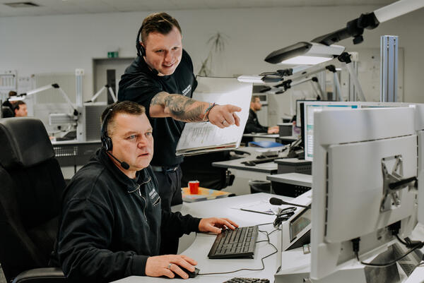 Zwei Mitarbeiter bei der Arbeit in der Leitstelle 