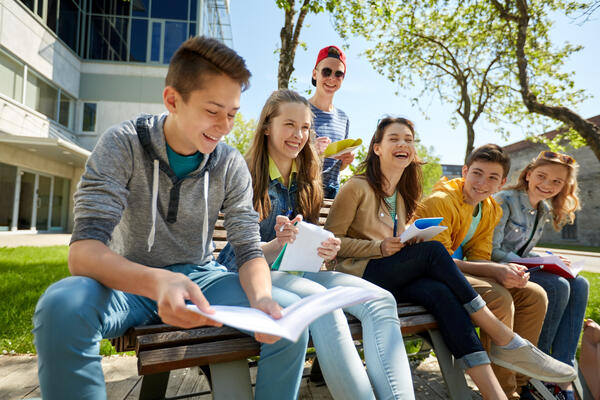 Eine Gruppe Schüler sitzen vor einem Schulgebäude